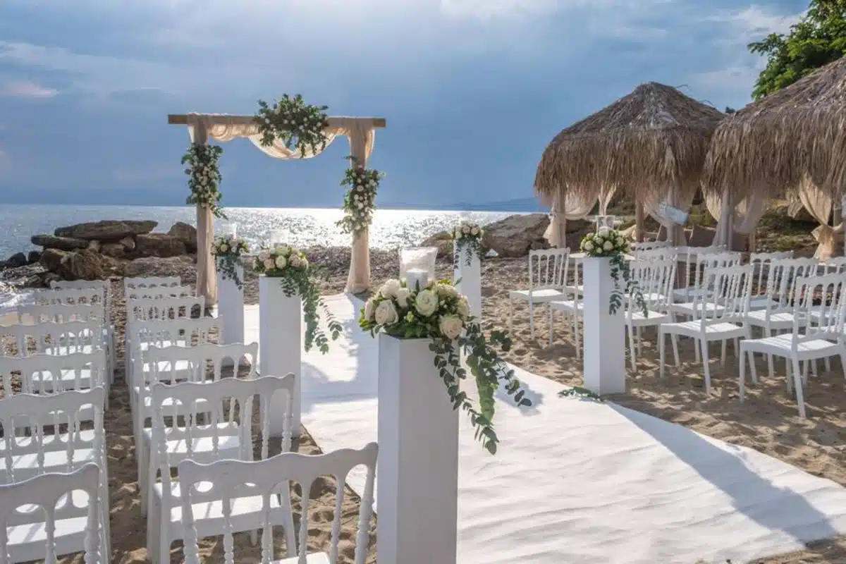 40-ani-casatorie-amplasare-decoratiuni-nunta-pe-plaja-arcada-dreptunghiulara-lemn-scaune-albe-traversa-alba-coloane-albe-aranjamente-florale